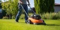 A professional caucasian gardener cuts a grassy lawn with a modern electric cordless mower. Landscape design theme