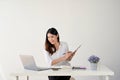 A businesswoman is taking notes on paper on a clipboard while looking at her laptop screen Royalty Free Stock Photo