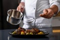 Professional chef adding sauce to delicious dish at table indoors, closeup Royalty Free Stock Photo