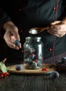 Professional chef adds sugar to the plums in the jar. Cooking or preserving sweet compote in the kitchen at home