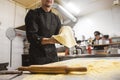 Professional chef cooking in the kitchen restaurant at the hotel, preparing dinner. A cook in an apron makes a pizza Royalty Free Stock Photo