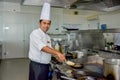 Professional chef cooking omlet on the skillet at the kitchen and smiling