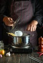 Professional chef cooks a delicious soup with vegetables and pasta in a hot pot in the kitchen. Delicious hotel food recipe Royalty Free Stock Photo