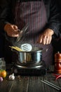 Professional chef cooks a delicious soup with vegetables and pasta in a hot pot in the kitchen. Delicious hotel food recipe Royalty Free Stock Photo