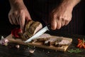 Professional chef cuts the grilled veal meat into small slices. Work environment on the kitchen table with condiments or spices. Royalty Free Stock Photo