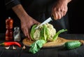 Professional chef cutting cauliflower in a restaurant kitchen. The idea of a delicious diet for breakfast or dinner Royalty Free Stock Photo
