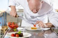 Professional chef decorates dessert cake with strawberry in kitchen