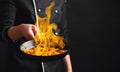 Professional chef and fire. Cooking vegetables and food over an open fire on a dark background. Hotel service photo