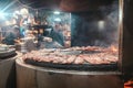 Professional chef grills pork or beef ribs on an open round grill oven in a restaurant for summer outdoor party.