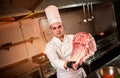 Professional chef holding raw bbq beef ribs on the background of vegetables. Chief chef preparing meat for grilling in the kitchen Royalty Free Stock Photo