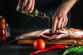 Professional chef prepares fresh fish bighead carp with add oil. Preparing to cook fish food. Working environment in restaurant or Royalty Free Stock Photo