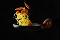 Professional chef prepares pasta, spaghetti with shrimps on a black background. Frozen in-flight food. Healthy vegetarian food,