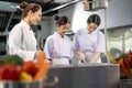 Professional chef is teaching young culinary class student to prepare fresh ingredient for the meal inside the restaurant kitchen Royalty Free Stock Photo