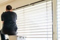 Professional cleaner deep cleaning window blinds in an apartment with a green microfiber cloth Royalty Free Stock Photo