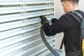 Professional cleaner vacuum cleaning window blinds on an apartment balcony Royalty Free Stock Photo