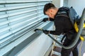 Professional cleaner vacuum cleaning window blinds on an apartment balcony Royalty Free Stock Photo
