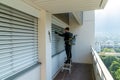 Professional cleaner vacuum cleaning window blinds on an apartment balcony Royalty Free Stock Photo
