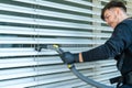 Professional cleaner vacuum cleaning window blinds on an apartment balcony Royalty Free Stock Photo