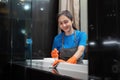 Professional cleaning service company employee in rubber gloves cleaning and detergent spray in bathroom