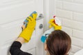 Professional cleaning services. Woman worker in rubber gloves doing cleaning in the bathroom, cleaning door with rag and detergent