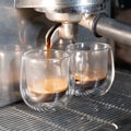A professional coffee machine pours coffee into glass cups