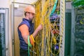 Professional communications guy unravels the wires in the data center server room. The specialist restores the Internet connection