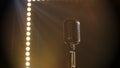 Professional concert vintage glare microphone. Mic for record or speak to audience on stage in empty retro club close up Royalty Free Stock Photo