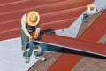 Professional construction worker changing the roof membrane of a building with metal roof sheet.