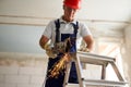 Professional construction worker hands in work gloves using angle grinder to cut metal rod at building site. Close up Royalty Free Stock Photo