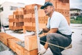 Professional construction worker laying bricks and building house in industrial site. Detail of hand adjusting bricks Royalty Free Stock Photo