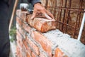 Professional construction worker laying bricks and building walls on industrial construction site. Detail of hand adjusting bricks Royalty Free Stock Photo