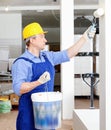 Professional construction worker priming and painting wall in repairable room with painting roller