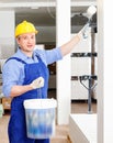 Professional construction worker priming and painting wall in repairable room with painting roller Royalty Free Stock Photo