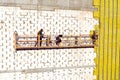 Professional construction Worker on scaffold elevator insulated wall facade with mineral wool. roofers wearing safety harness