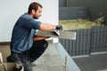 Professional construction worker, tiler laying adhesive and placing ceramic tiles on waterproof floor Royalty Free Stock Photo