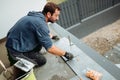 Professional construction worker, tiler laying adhesive and placing ceramic tiles on waterproof floor. Royalty Free Stock Photo