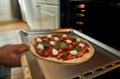 Professional cook making pizza at home. Close up of hand of man putting raw pizza in modern oven for baking. Hobby Royalty Free Stock Photo