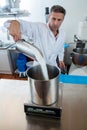 Professional cook pouring sugar to weight it on industrial scale