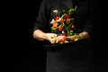 Professional cook. He prepares a dish with vegetables in a saucepan. on black background, menu, recipe book, healthy food