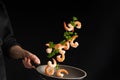 Professional cook prepares shrimp with green parsley. Cooking seafood, healthy vegetarian food and meal on a dark background.