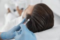 Cosmetologist in gloves does vitamin injection in patient head skin during meso therapy