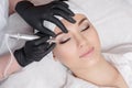 Professional cosmetologist wearing black gloves making permanent makeup Royalty Free Stock Photo