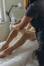 Professional cosmetologist woman removes all bandages after the procedure of wrapping in a beauty salon.