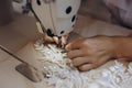 The professional crafter is sewing an ornament on the table with the help of machine