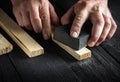 Professional craftsman cleans the wood plank with an abrasive tool. Builder hands close up. Renovation or construction idea