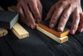 Professional craftsman cleans the wood plank with an abrasive tool. Builder hands close up. Renovation or construction idea