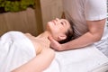 Professional cropped therapist doing healthy massage on neck and shoulders to female client