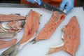 Professional cutting of raw red salmon fish. Hands with a knife close-up. Fish factory, shop, production, restaurant.