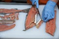 Professional cutting of raw red salmon fish. Hands with a knife close-up. Fish factory, shop, production, restaurant.