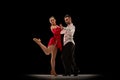 Professional dancers. Performance. Young man and woman dancing classical tango, ballroom over black background. Concept